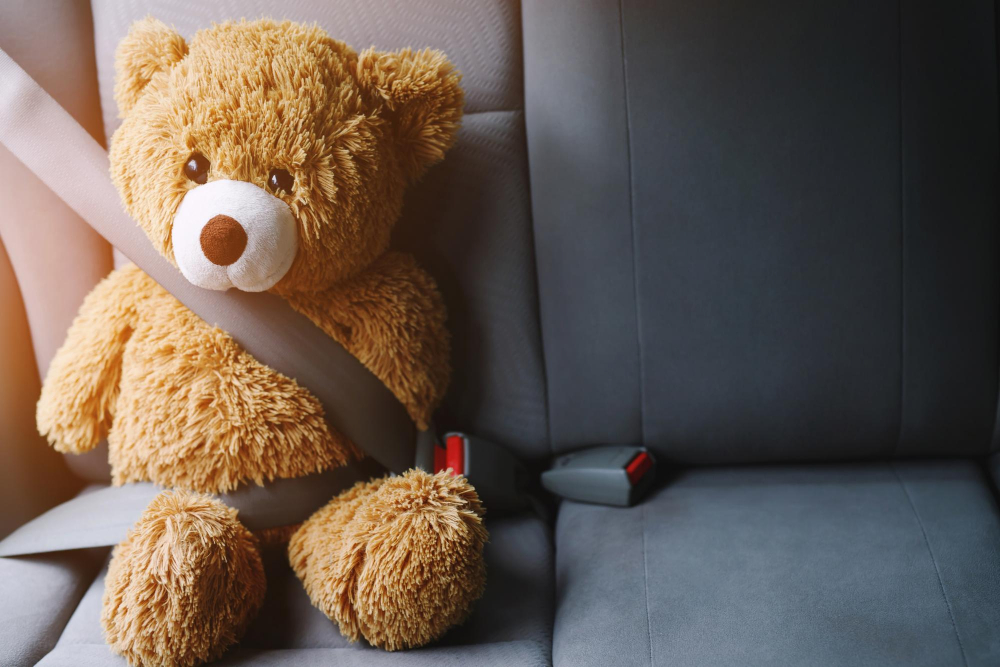 brown teddy bear wearing car seat belt