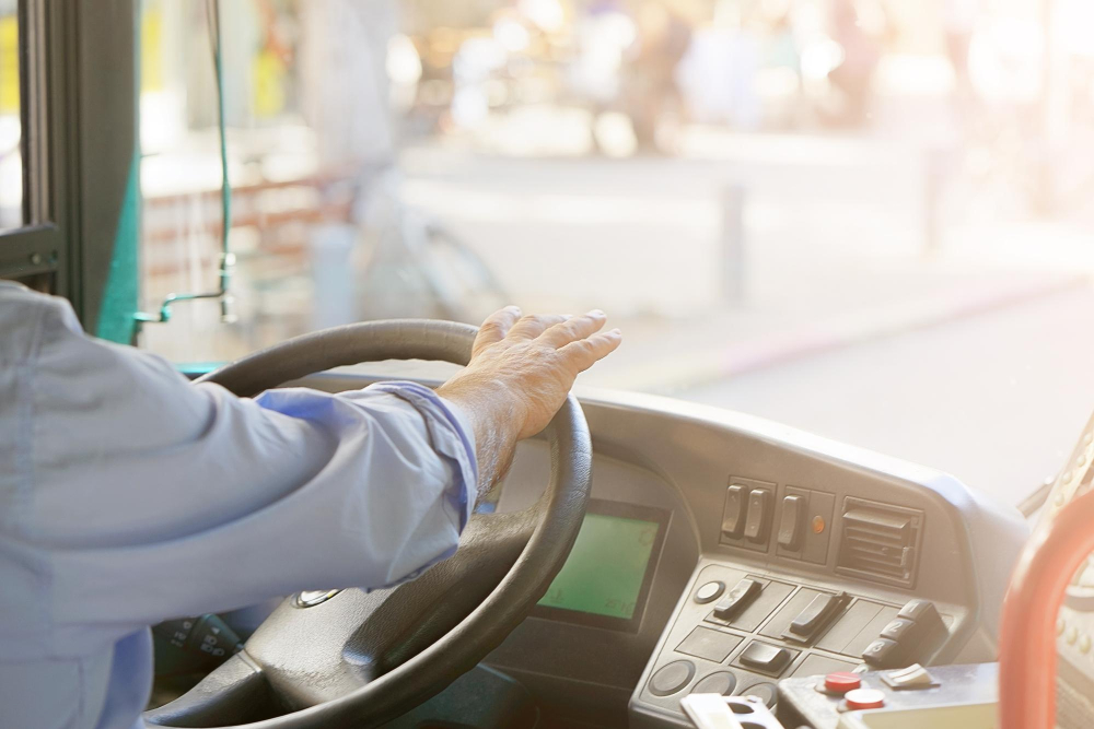 cropped shot bus driver holding steering whee