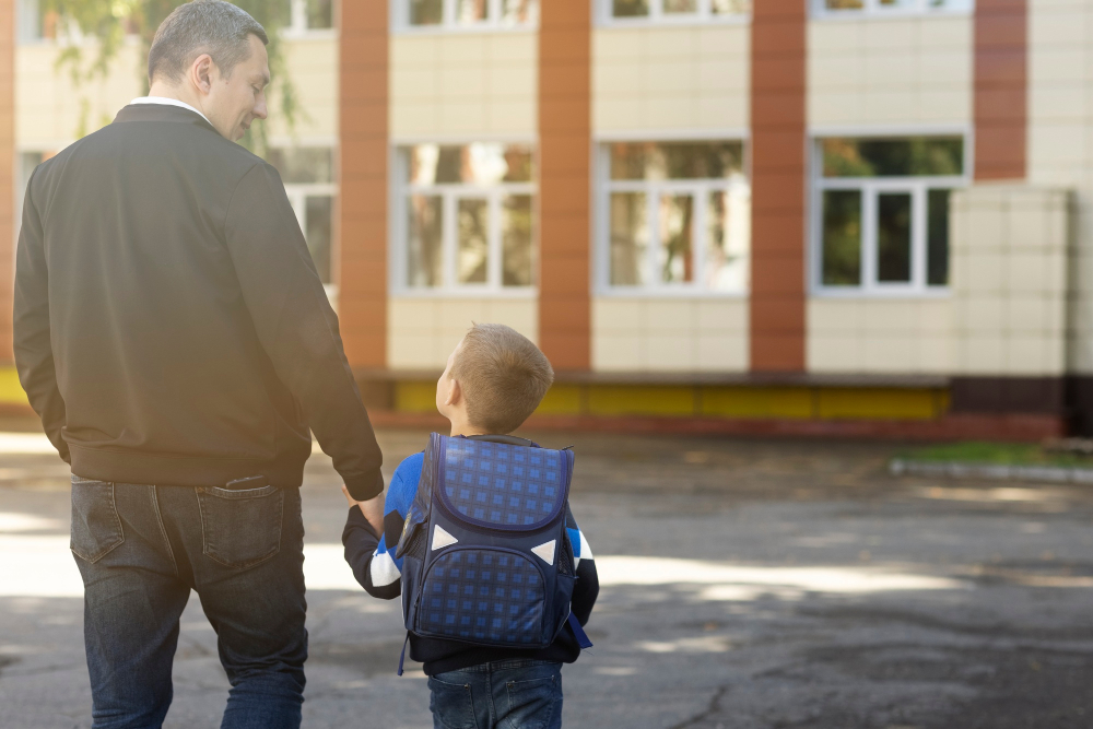 father kid first school day back view